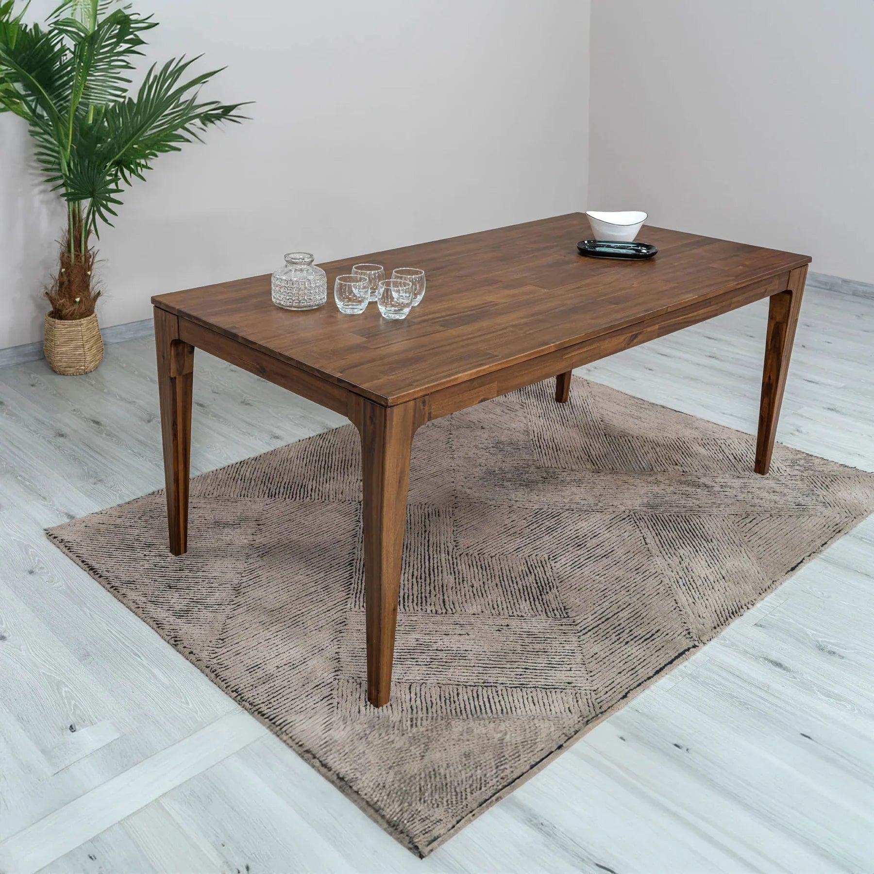 Front view of the Allure dining table in a rich walnut-toned acacia wood featuring a minimalist rectangular top and flared tapered legs