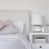Close-up lifestyle shot of the headboard styled with white pillows and a modern bedside lamp