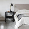 Close-up lifestyle perspective of the headboard corner styled with a black modern nightstand and adjustable reading lamp