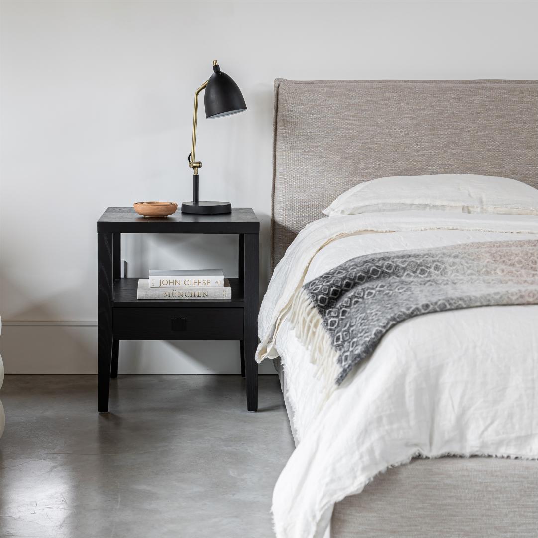 Close-up lifestyle perspective of the headboard corner styled with a black modern nightstand and adjustable reading lamp