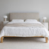 Lifestyle shot featuring the Luna bed styled with white linen bedding and a textured throw in a bright airy room