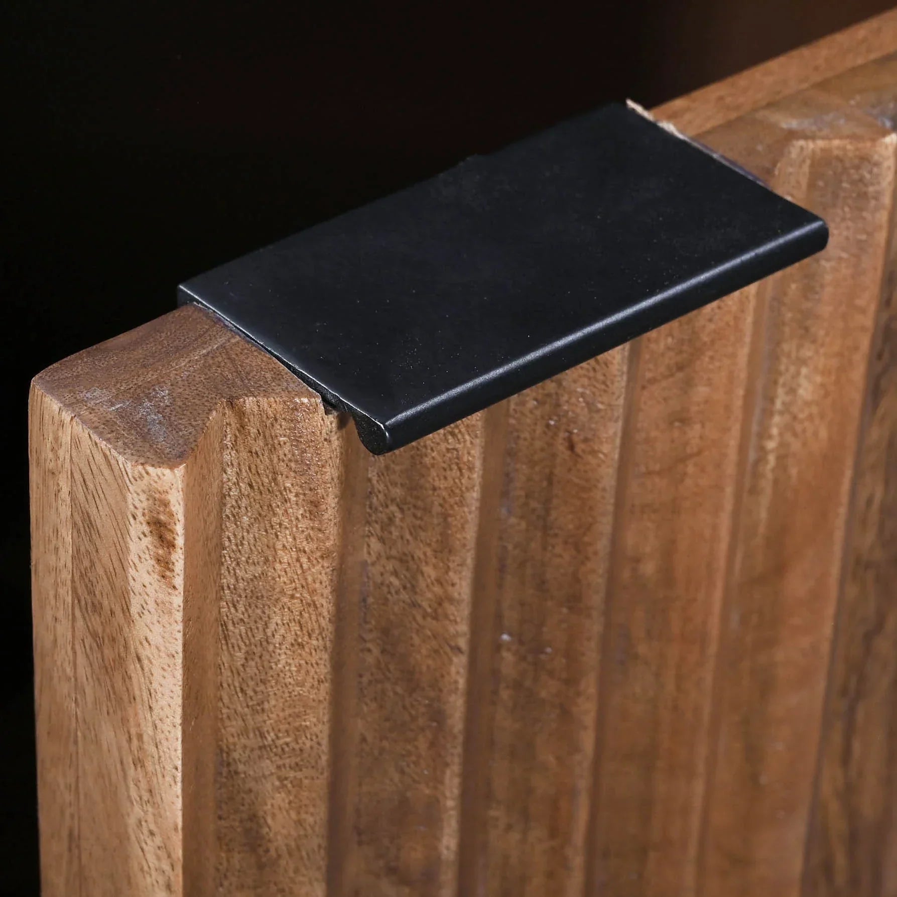 Front view of the Nikita sideboard featuring a warm wood finish with intricate chevron-patterned ribbed door panels and slim black metal legs