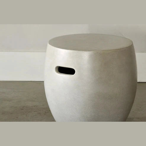 Front view of a minimalist barrel-shaped side table made from off-white fiber cement with a built-in horizontal handle cutout
