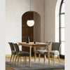 Studio lifestyle shot featuring the Kenzo dining table paired with four grey upholstered chairs in a bright, modern dining space