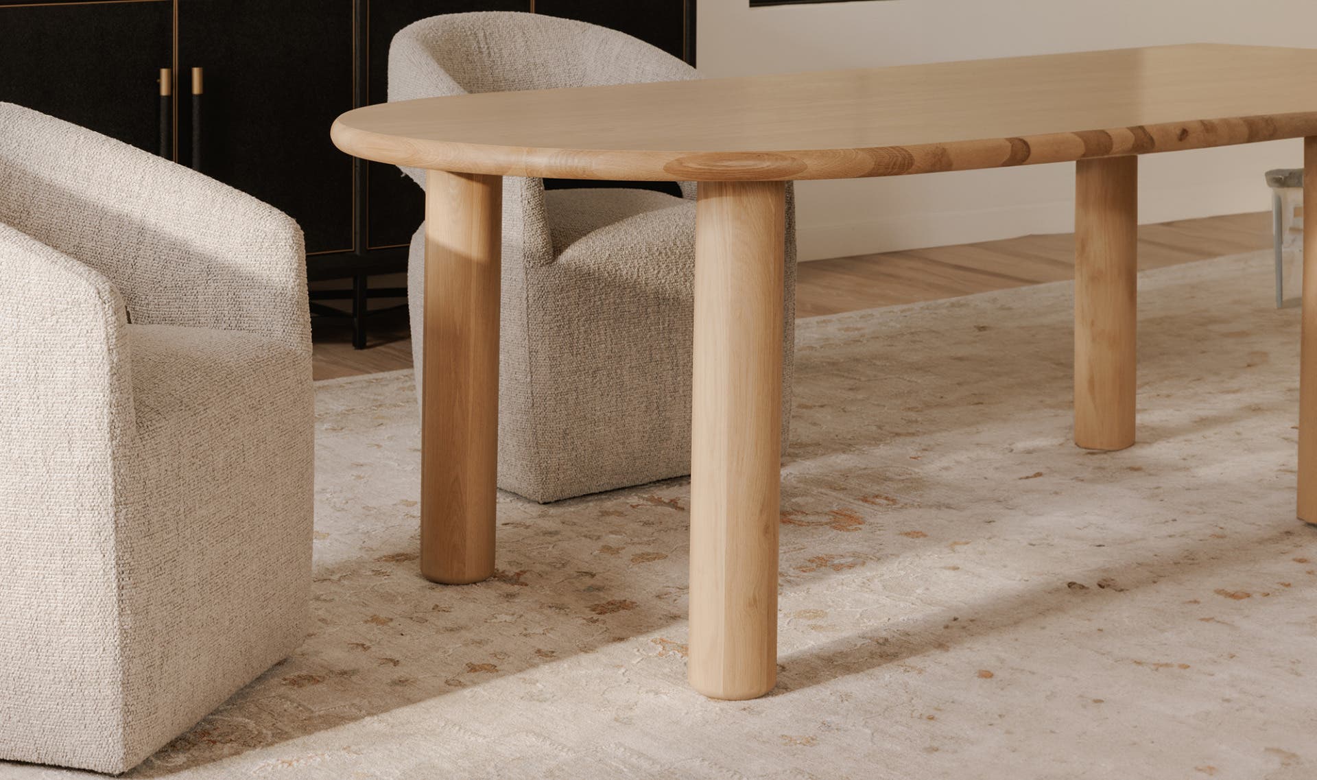 Front view of the Milo small dining table featuring a light natural oak finish, smooth oval tabletop, and four thick cylindrical wooden legs