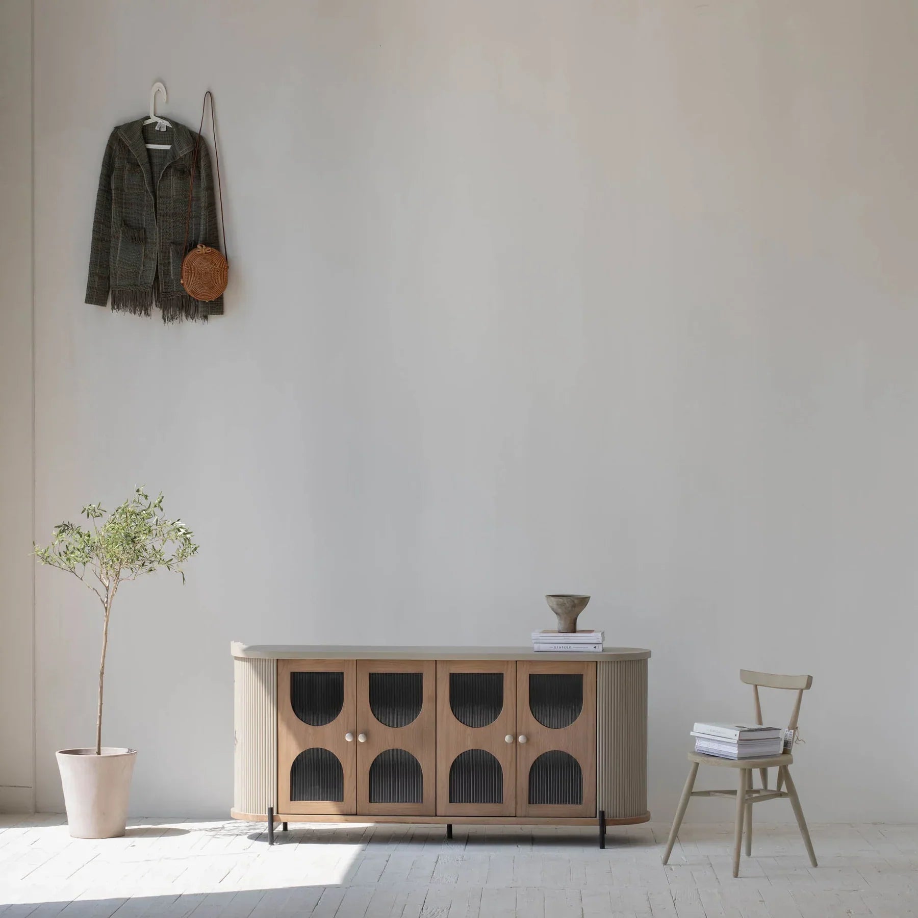 Lifestyle shot featuring the Colosseo sideboard styled in a bright minimalist room with a single plant and neutral wall decor