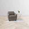 Lifestyle view of the marble side table paired with a grey upholstered armchair and a small plant in a bright minimalist room