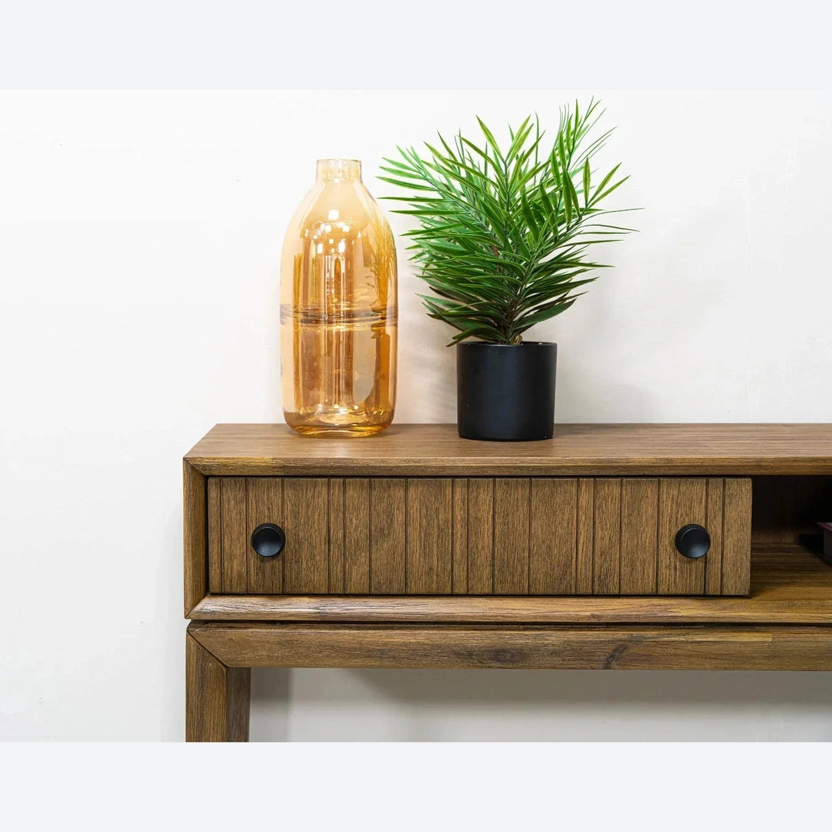 Front view of the West console table in a rich wood finish featuring a slim architectural frame, an integrated drawer with fluted texture, and an open storage cubby