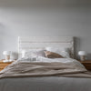 Straight-on lifestyle view highlighting the clean architectural lines of the tall headboard against a neutral white wall