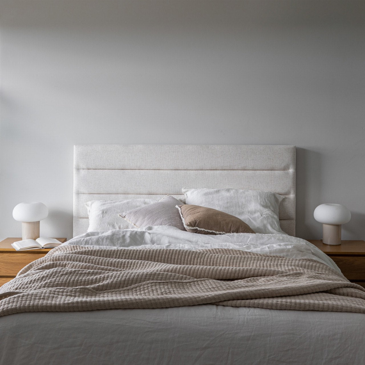 Straight-on lifestyle view highlighting the clean architectural lines of the tall headboard against a neutral white wall
