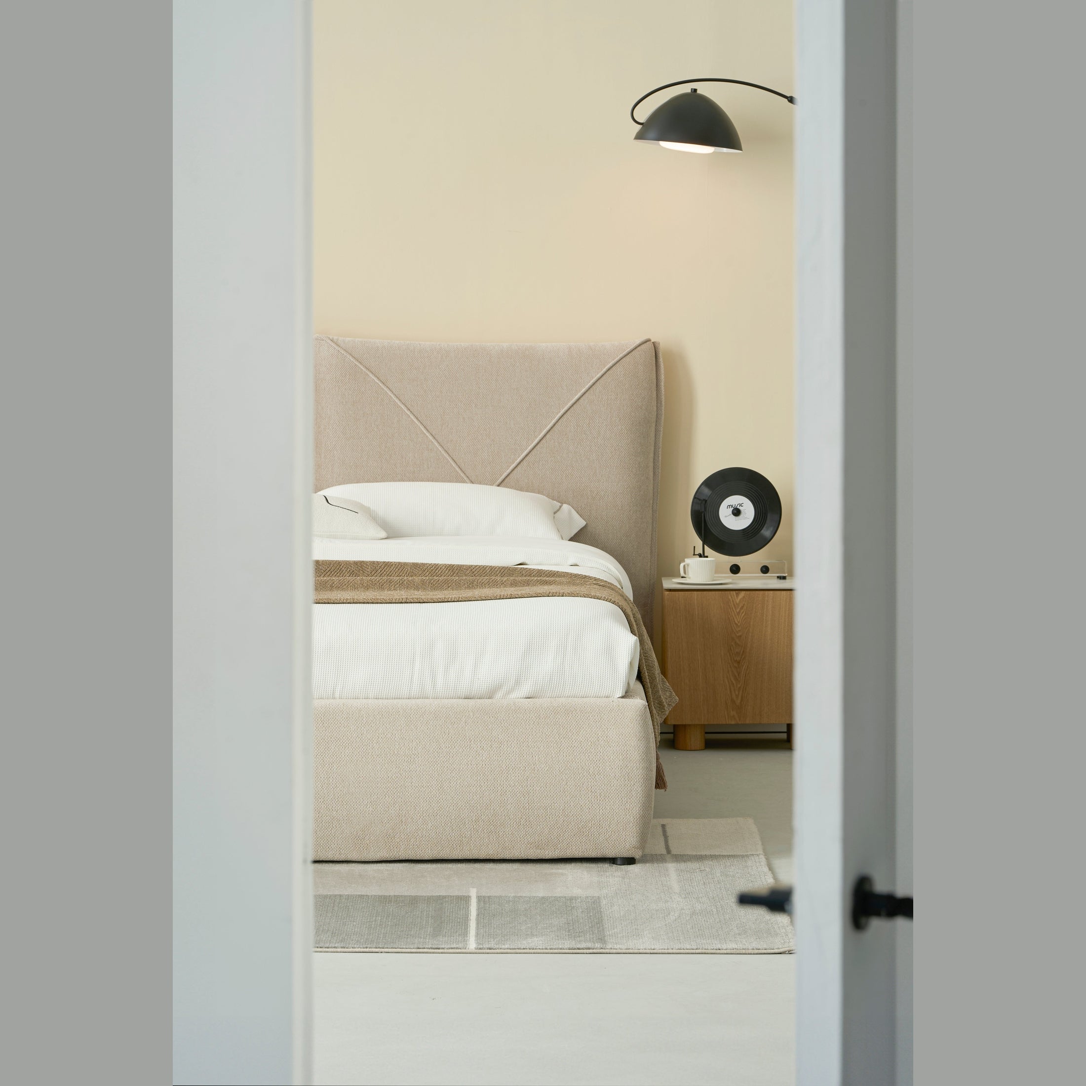 Front view of the Aici storage bed featuring a cream fabric finish and a unique V-shaped geometric stitched headboard