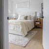 Perspective view from a doorway highlighting the inviting and cozy aesthetic of the tall cream storage bed