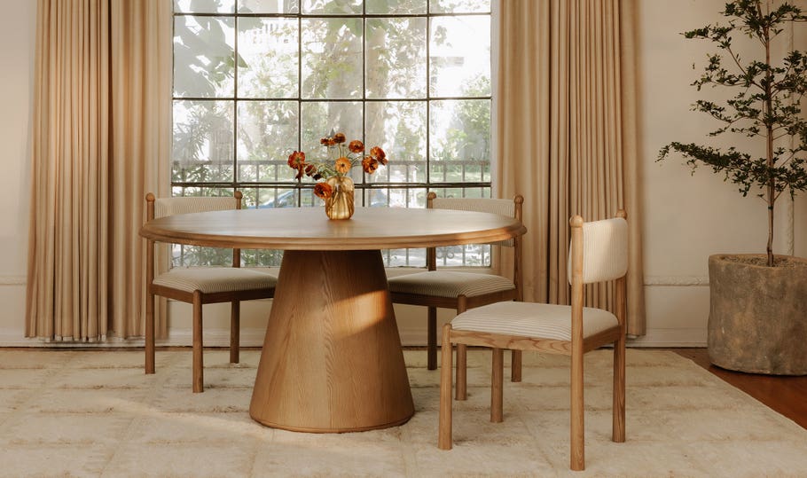 Front view of the Tutto round dining table featuring a light natural wood finish and a minimalist conical pedestal base