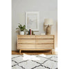 Wide lifestyle shot featuring the dresser styled in a bright, neutral bedroom setting with a contemporary lamp
