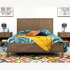 Lifestyle shot featuring the West bed styled with teal floral bedding and a vibrant mustard throw in a bright master suite