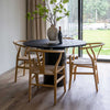 Lifestyle shot of the Alter table styled with natural wood wishbone chairs in a bright modern dining room