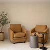 Interior view showing the dark grey side table between two tan armchairs in a bright contemporary seating area