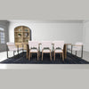 Lifestyle shot of the cabinet positioned in a dining space paired with white chairs and a dark navy rug