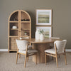 Lifestyle shot featuring the Terra table styled in a warm minimalist dining room with an arched hutch and neutral upholstered chairs