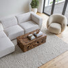 High-angle room shot showing the Estelle chair paired with a rustic wood coffee table and textured rug.