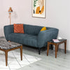 Lifestyle view of the black marble side table styled next to a dark teal upholstered sofa in a contemporary living space