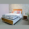 Wide lifestyle view of the bed in a studio setting with a white brick wall and coordinating wood nightstands