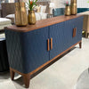 Elevated lifestyle shot of the navy blue Eden sideboard styled with gold vases in a bright, professional showroom setting