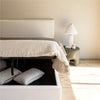 Lifestyle perspective of the Julia bed styled with layered neutral blankets and artistic framed wall decor