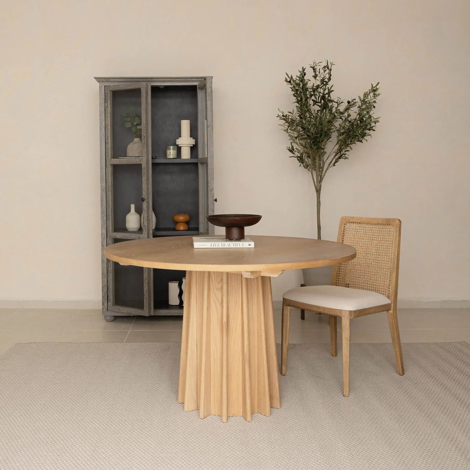 Front view of the Sculpture round dining table featuring a natural oak finish and a striking fluted pedestal base
