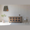 Lifestyle shot highlighting the sideboard height and scale styled with a neutral chair and potted plant