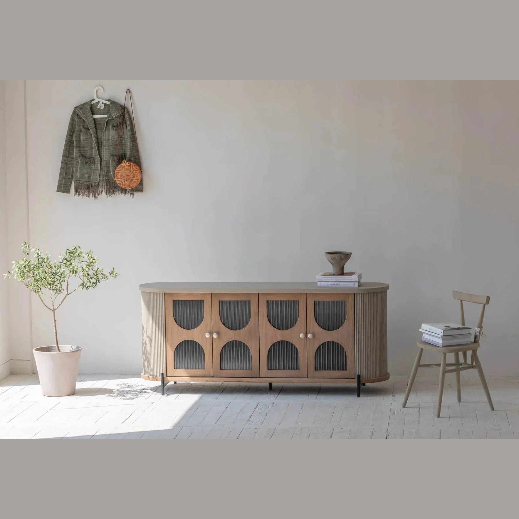 Lifestyle shot highlighting the sideboard height and scale styled with a neutral chair and potted plant