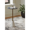 Lifestyle shot of the Caramont table with a black marble top styled in a contemporary living room next to a green plant
