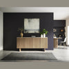 Lifestyle shot of the fluted oak sideboard styled against a dark accent wall with contemporary art and greenery