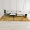 Lifestyle view of the Nila coffee table styled in a bright modern living room with a white sectional sofa and a large golden-toned area rug