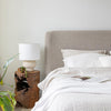 Lifestyle view of the 21-inch teak root table used as a rustic modern nightstand in a bright minimalist bedroom