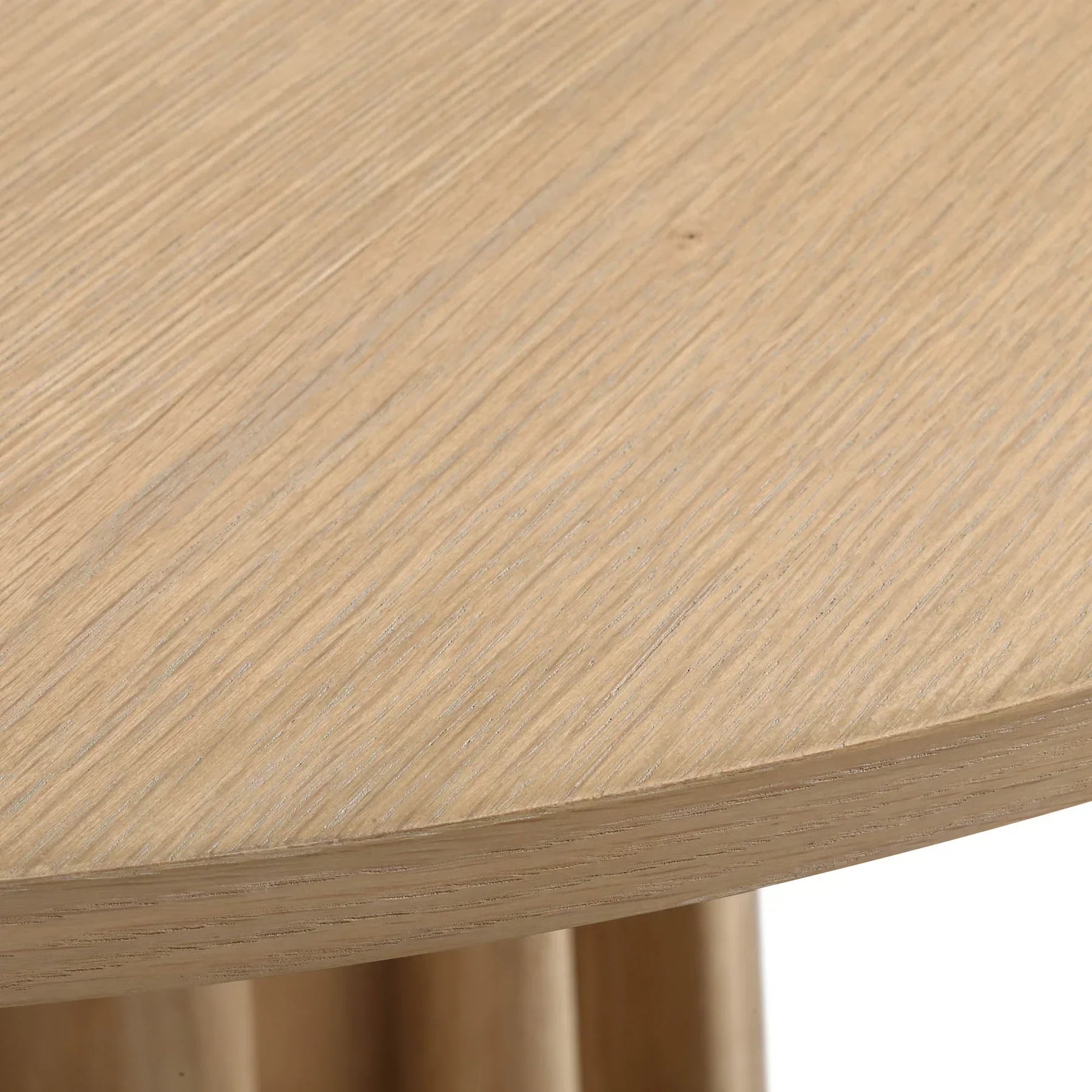 Front view of the Sculpture round dining table featuring a natural oak finish and a striking fluted pedestal base