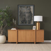 Lifestyle shot featuring the natural oak sideboard styled with metallic accessories and greenery against a dark wall