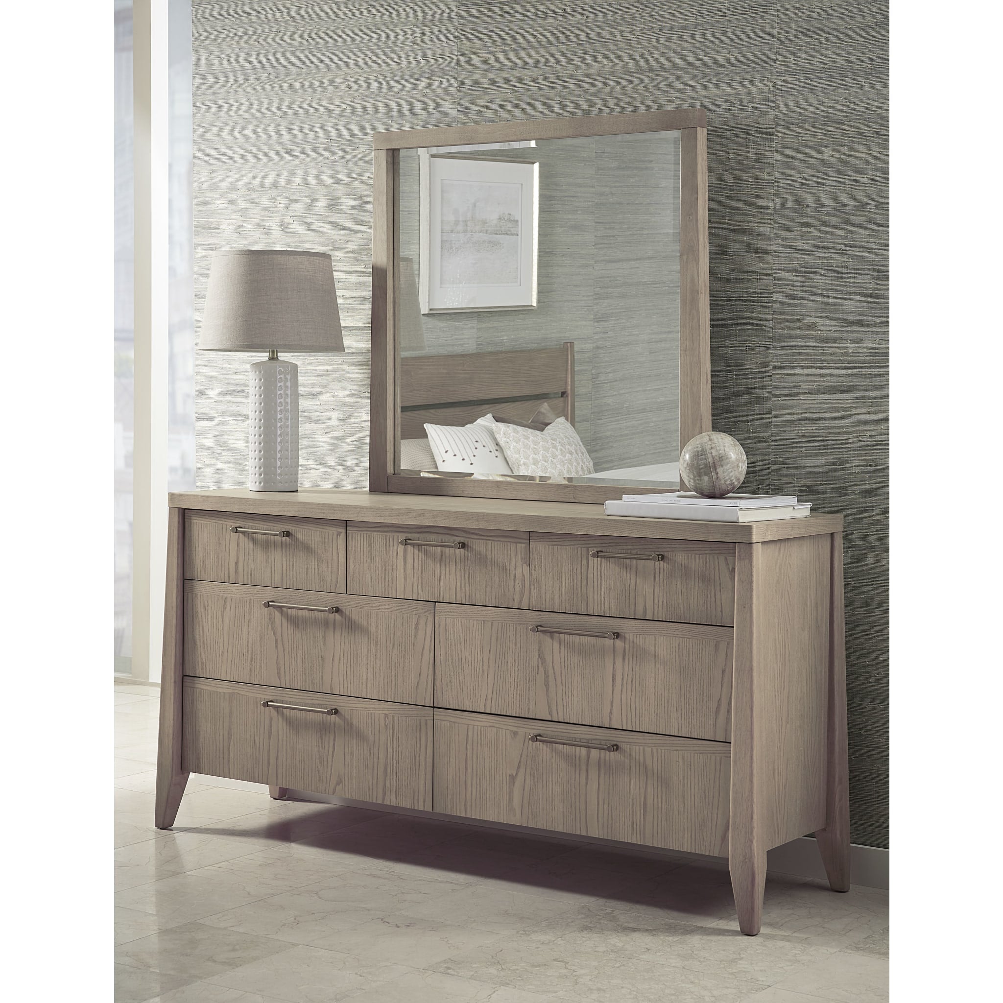 Studio lifestyle shot featuring the Nettie dresser and mirror styled with a modern lamp and vase against a textured gray wall