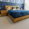 Lifestyle shot of the bed styled with deep blue velvet linens against a navy blue paneled wall