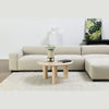 Wide lifestyle view showing the Nils coffee table centered on a neutral area rug with minimalist wall art in the background