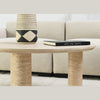 Side-angle lifestyle view showing the Nils table paired with a large cream sofa for a sophisticated monochromatic look