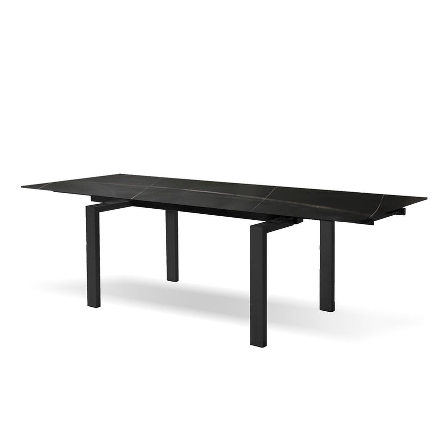Perspective view of the Odd dining table featuring a Shakespeare Black porcelain top with subtle white veining and architectural black steel legs