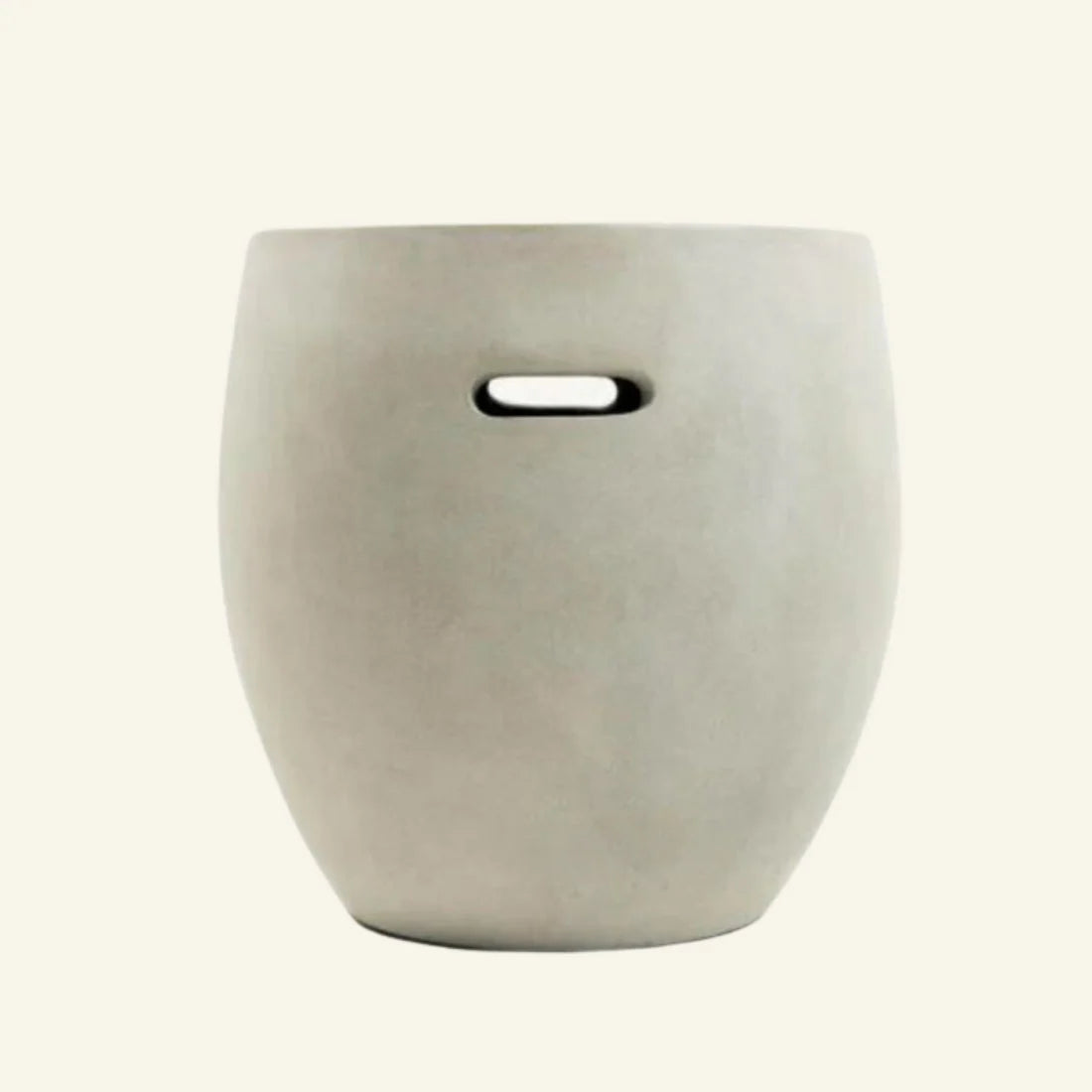 Front view of a minimalist barrel-shaped side table made from off-white fiber cement with a built-in horizontal handle cutout