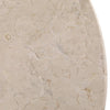 Macro detail view of the cream-colored stone tabletop showcasing its organic pitted texture and smooth finish
