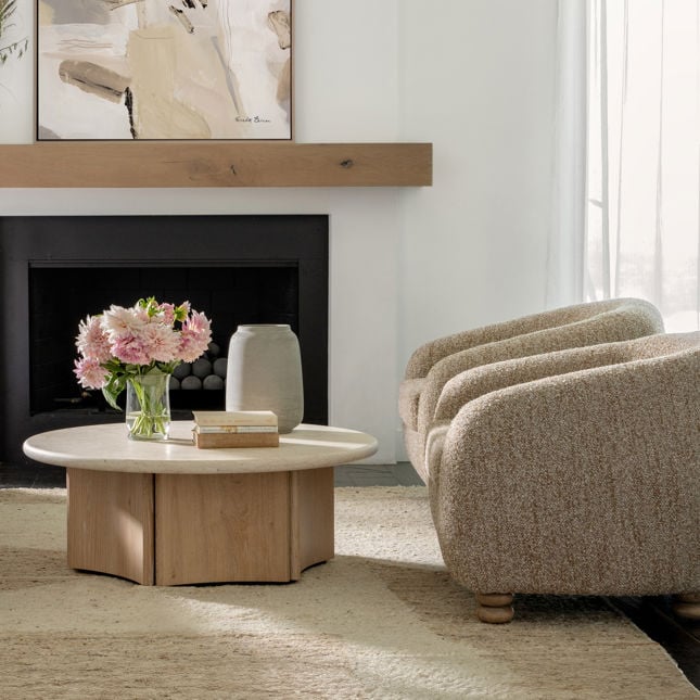 Wide shot showing the Oja coffee table paired with boucle accent chairs near a fireplace for a cozy modern look