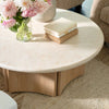 Lifestyle shot featuring the Oja coffee table styled with flowers and books in a bright contemporary living room