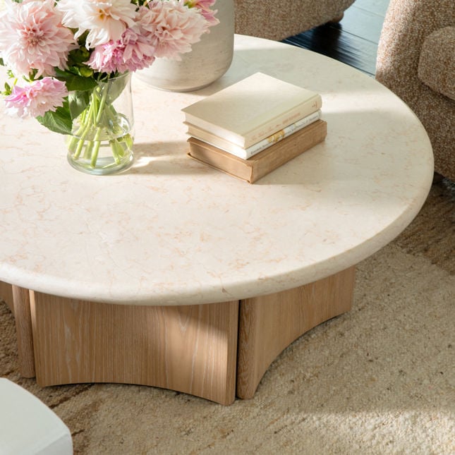 Lifestyle shot featuring the Oja coffee table styled with flowers and books in a bright contemporary living room