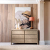 Studio lifestyle shot featuring the Opera dresser styled with modern art and a table lamp against a textured wood wall