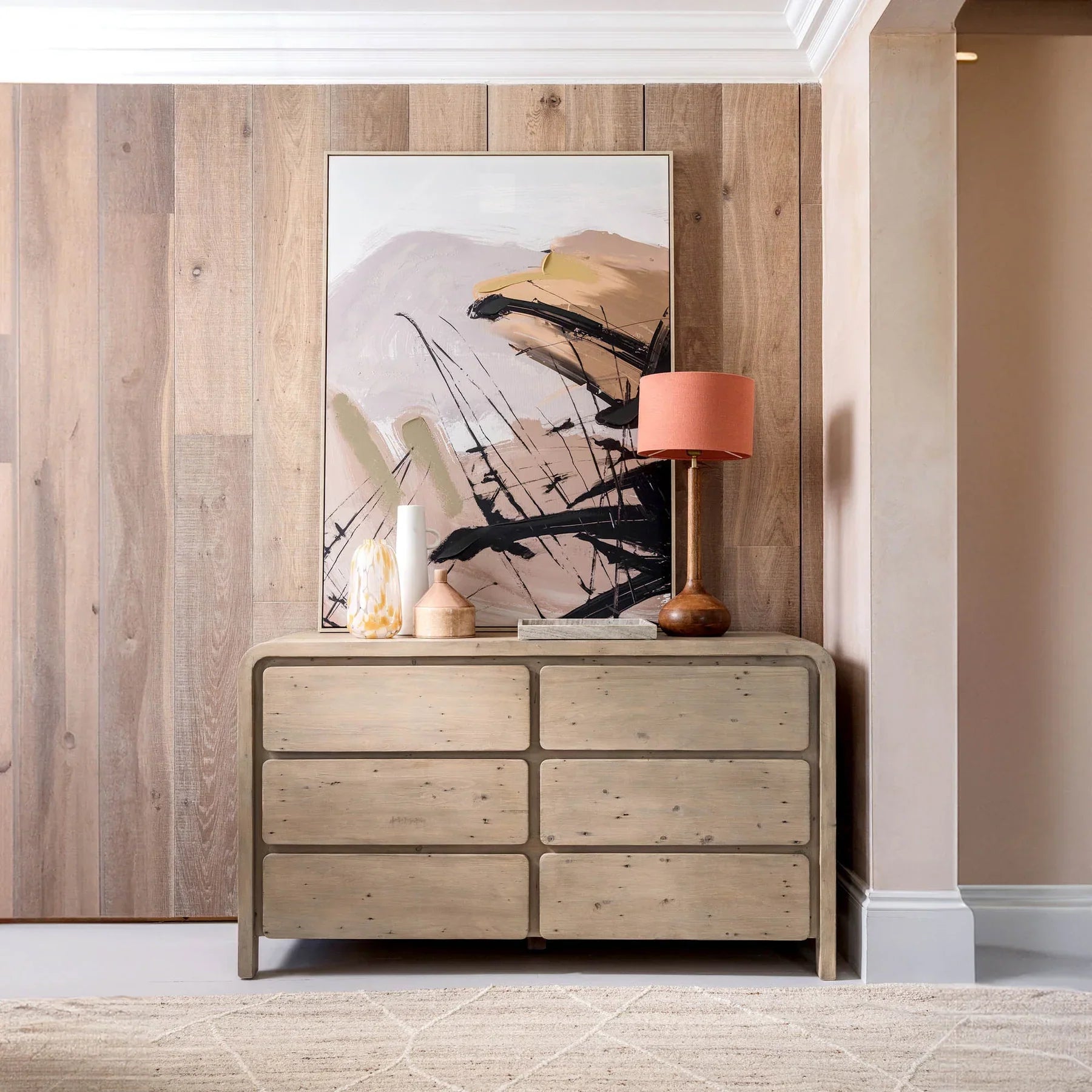 Studio lifestyle shot featuring the Opera dresser styled with modern art and a table lamp against a textured wood wall