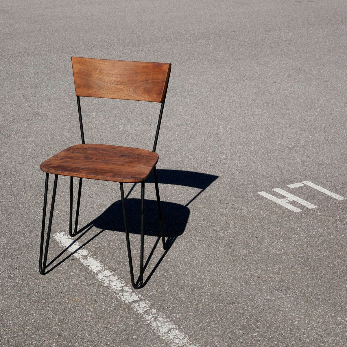 Front view of the Organic chair featuring a solid wood seat and backrest with black metal hairpin legs